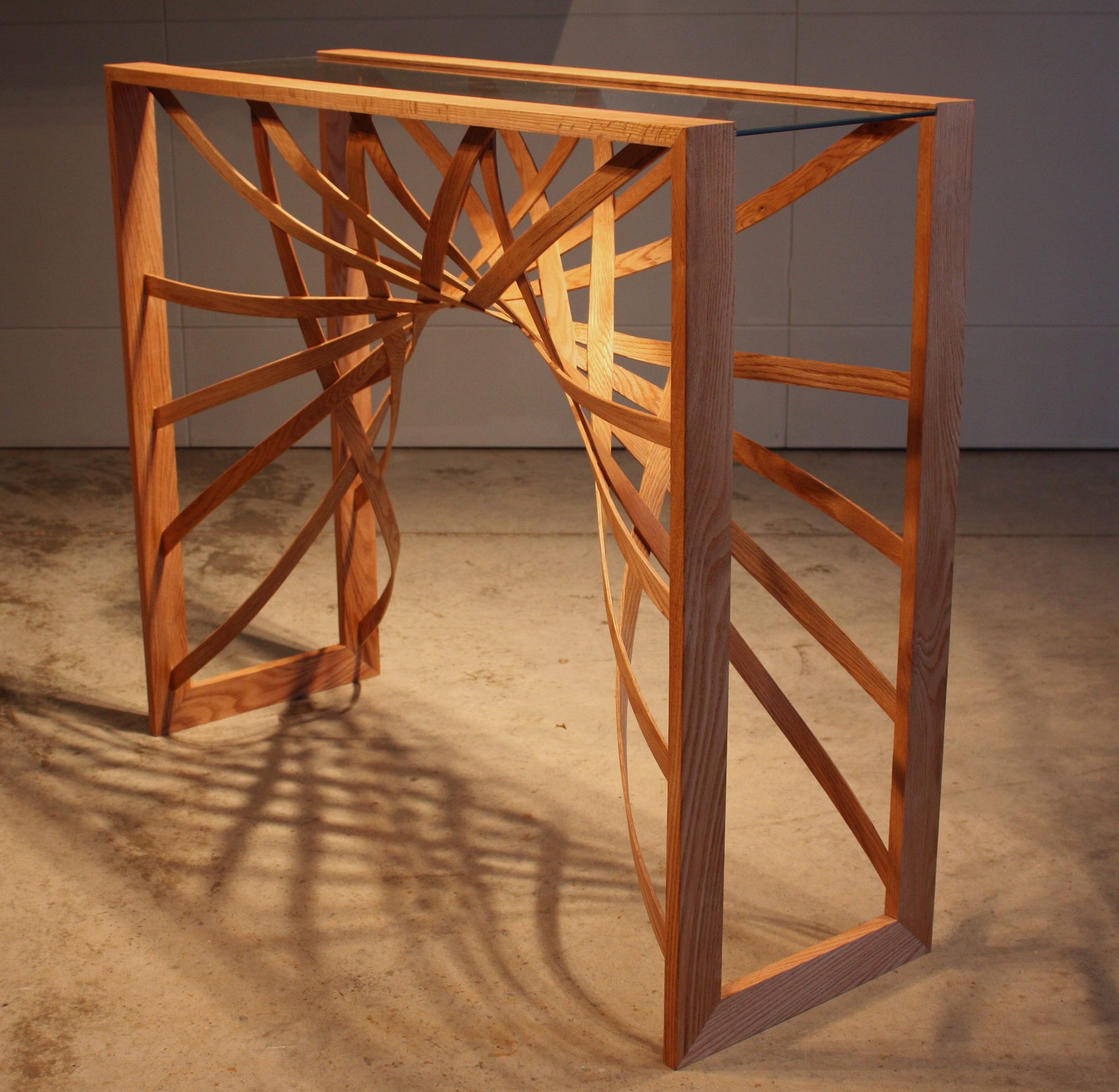 Console table, Bent-wood bands twisting through a glass-topped frame